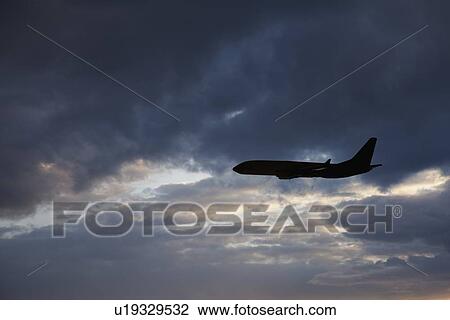 Stock Image - Commercial jet in cloudy sky. Fotosearch
