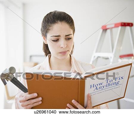 Stock Image - Confused woman reading do it yourself book. Fotosearch