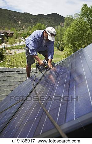 Construction worker installing solar panel on roof View Large Photo Image Stock Photo - Construction worker installing solar panel on roof. Fotosearch