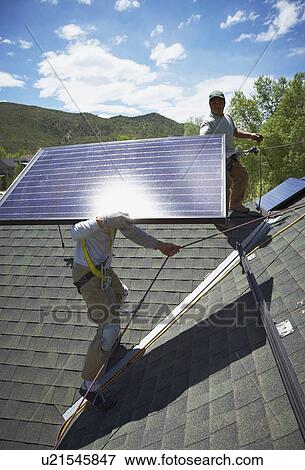 Construction workers installing solar panels on roof View Large Photo Image Stock Photo - Construction workers installing solar panels on roof. Fotosearch