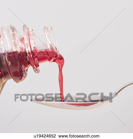 Stock Image - Cough syrup being poured onto spoon. Fotosearch