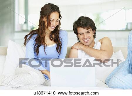 Stock Image - Couple looking at laptop together. Fotosearch