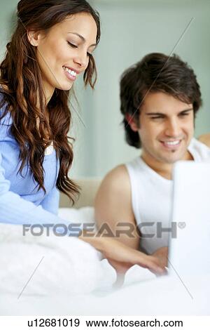 Couple looking at laptop together View Large Photo Image Stock Photo - Couple looking at laptop together. Fotosearch