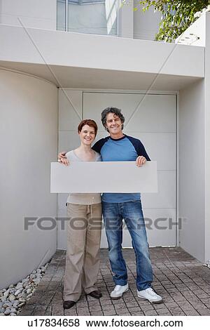 Stock Photo - Couple standing in front of their home. Fotosearch