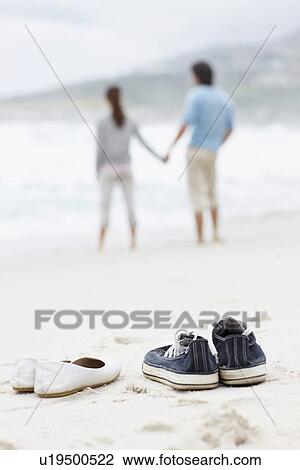 Stock Image - Couple walking barefoot at the beach. Fotosearch