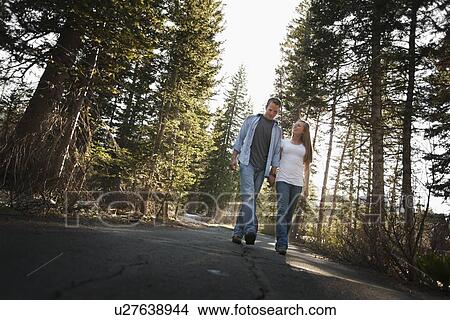 Couple walking hand in hand on a country road View Large Photo Image Picture - Couple walking hand in hand on a country road. Fotosearch