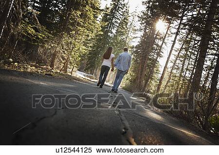 Couple walking hand in hand on a country road View Large Photo Image Stock Photography - Couple walking hand in hand on a country road. Fotosearch