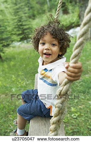 Stock Photo - Cute young child sitting on swing. Fotosearch