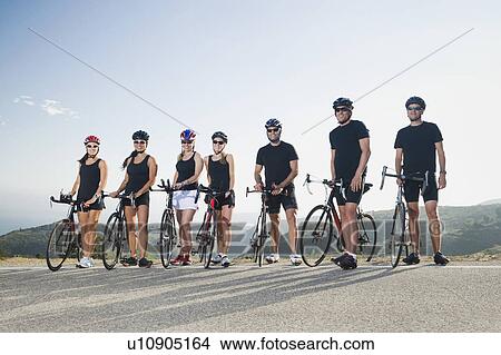 Picture - Cyclists standing beside their bikes on the side of the road. Fotosearch