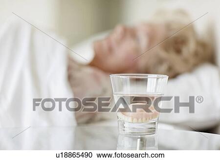 Stock Image - Dentures in a glass of water. Fotosearch