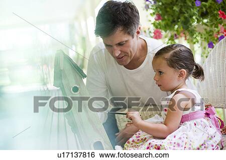 Stock Photograph - Father helping his daughter paint a birdhouse. Fotosearch