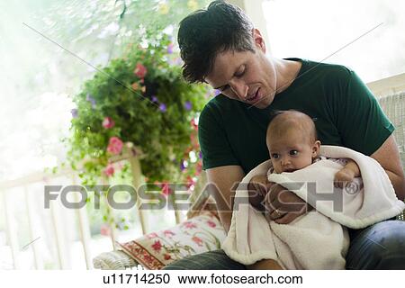Stock Image - Father sitting on porch with his baby daughter. Fotosearch