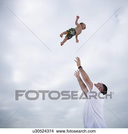 Father throwing young child in the air View Large Photo Image Picture - Father throwing young child in the air. Fotosearch