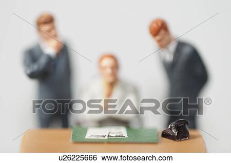 Figurines standing behind person at desk View Large Photo Image Stock Photograph - Figurines standing behind person at desk. Fotosearch