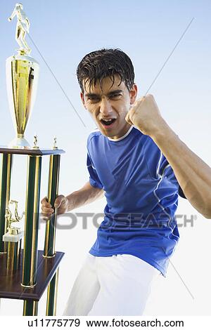 Stock Photo - Football player holding trophy. Fotosearch