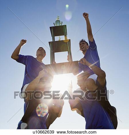 Stock Photo - Football players holding trophy. Fotosearch