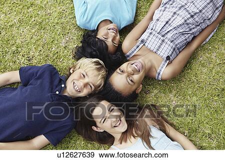 Four friends lying on the grass View Large Photo Image Stock Photo - Four friends lying on the grass. Fotosearch