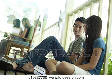 Stock Image - Friends sitting on porch floor. Fotosearch