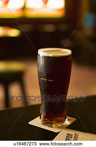 Stock Image - Glass of Irish ale in pub. Fotosearch