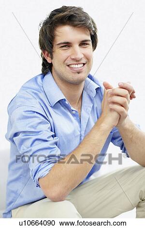 Stock Image - Handsome man sitting with hands clasped. Fotosearch
