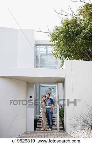 Stock Photo - Happy couple embracing in front of their home. Fotosearch