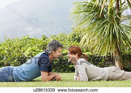 Happy couple lying face to face on the grass View Large Photo Image Stock Photo - Happy couple lying face to face on the grass. Fotosearch