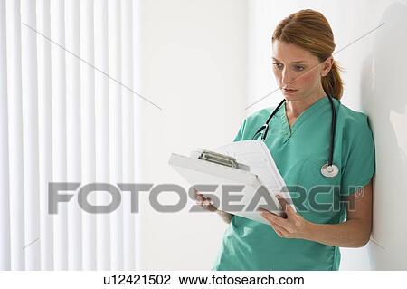 Stock Image - Healthcare worker looking at medical chart. Fotosearch