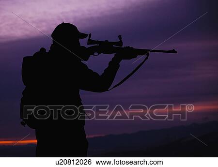 Stock Photograph - Hunter looking through scope of rifle. Fotosearch