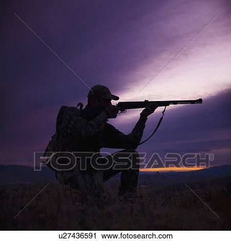 Stock Image - Hunter pointing his rifle. Fotosearch