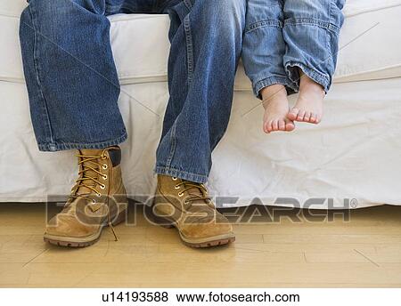Legs of two people sitting on couch View Large Photo Image Stock Photo - Legs of two people sitting on couch. Fotosearch