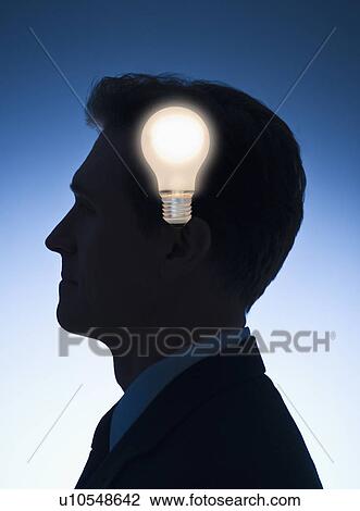Stock Image - Light bulb in front of profile of a businessman. Fotosearch