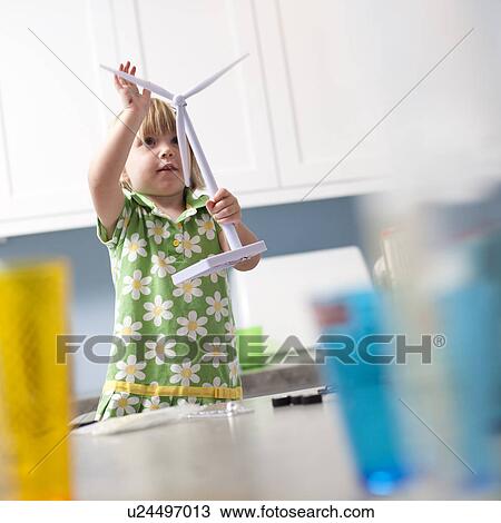 Stock Image - Little girl looking at model windmill. Fotosearch