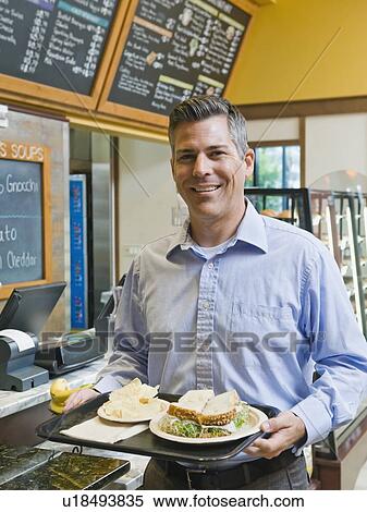 Stock Photography - Man carrying sandwich on tray. Fotosearch