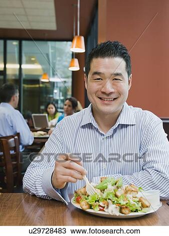 Stock Image - Man eating salad in restaurant. Fotosearch