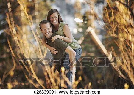 Stock Image - Man giving girlfriend a piggyback ride. Fotosearch