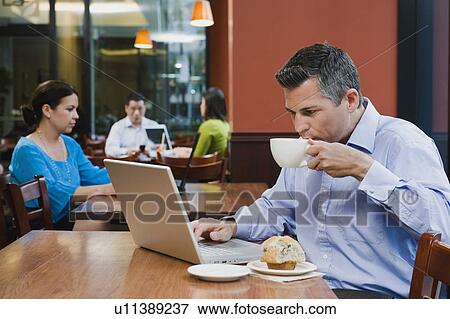 Stock Photo - Man working on laptop in restaurant. Fotosearch