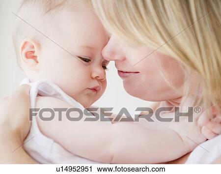 Stock Image - Mother embracing her baby daughter. Fotosearch
