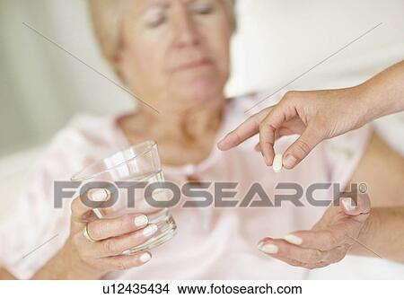 Picture - Nurse giving pill to senior woman. Fotosearch