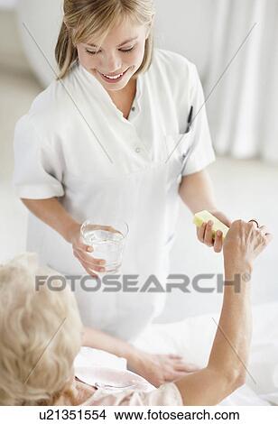 Picture - Nurse giving pill to senior woman. Fotosearch