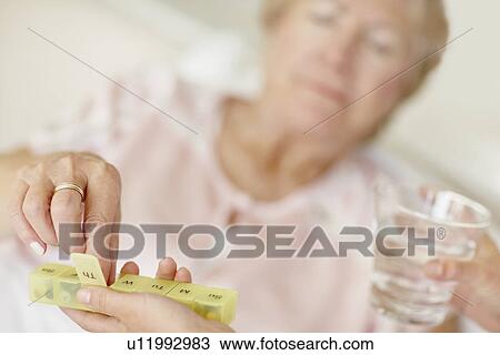 Stock Image - Nurse giving pill to senior woman. Fotosearch