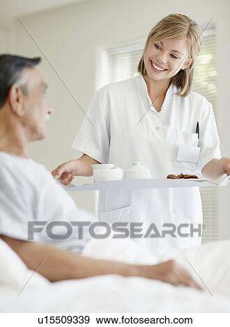 Nurse giving tray of food to patient View Large Photo Image Stock Photo - Nurse giving tray of food to patient. Fotosearch