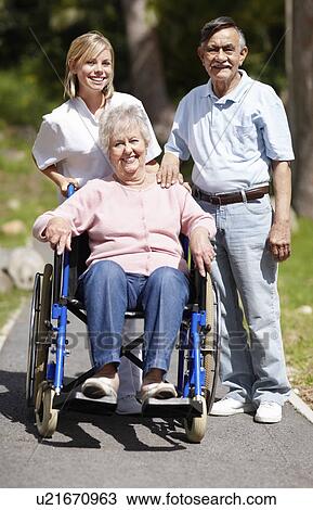 Stock Image - Nurse pushing senior woman in a wheelchair. Fotosearch