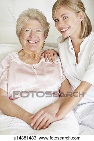 Stock Image - Nurse sitting with a senior woman. Fotosearch