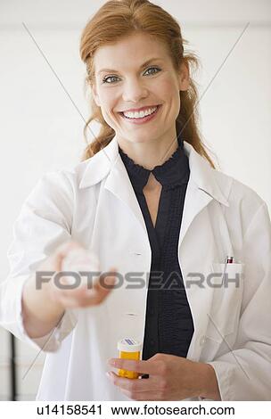Stock Image - Pharmacist holding bottle of prescription medication. Fotosearch