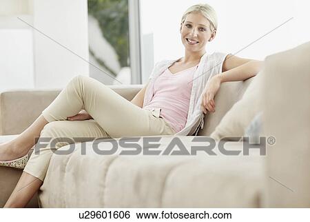 Pretty blond woman sitting on couch View Large Photo Image Stock Photograph - Pretty blond woman sitting on couch. Fotosearch