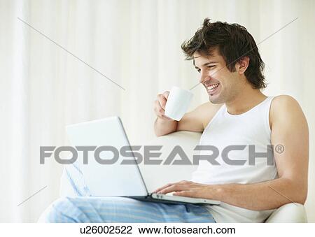 Stock Image - Relaxed man browsing the internet. Fotosearch