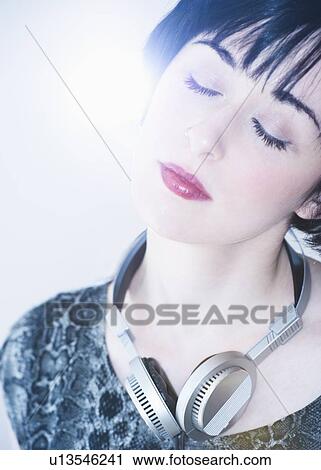 Stock Image - Relaxed woman with headphones around her neck. Fotosearch