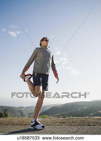 Runner stretching on the side of the road View Large Photo Image Stock Image - Runner stretching on the side of the road. Fotosearch