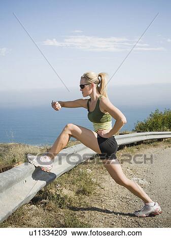 Stock Photo - Runner stretching on the side of the road. Fotosearch