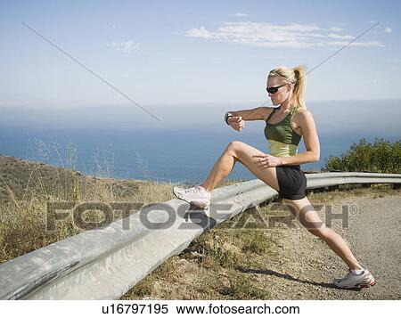 Stock Photography - Runner stretching on the side of the road. Fotosearch